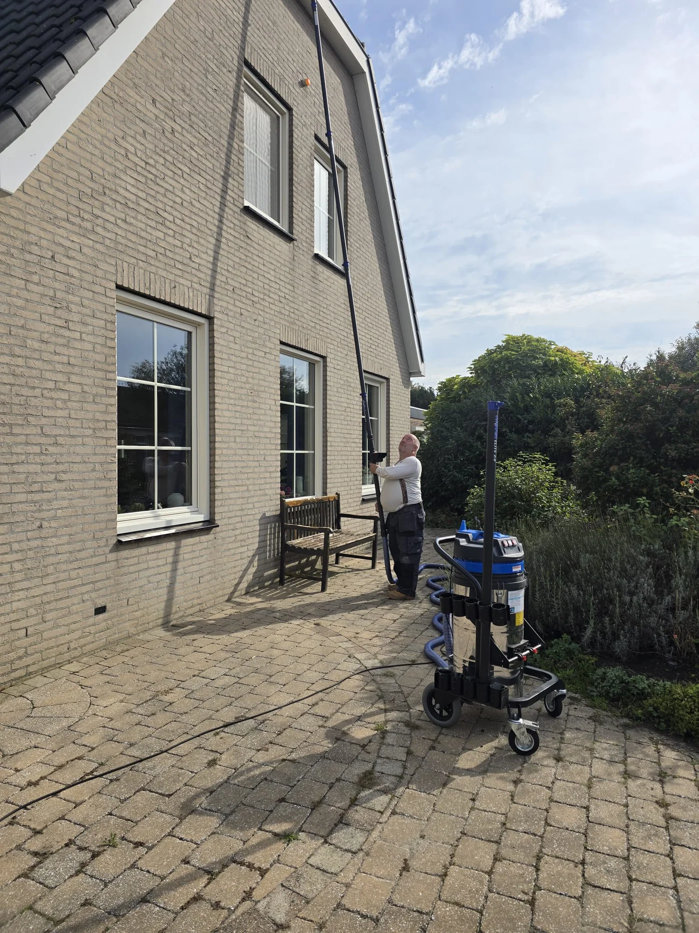 Peter met de volledige gootzuiger, slang en lange zuigbuis tot aan de dakgoot